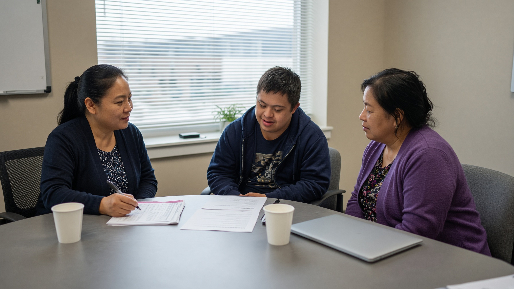 A case manager sits with a young man and his mother looking at job listings and a one-page plan.