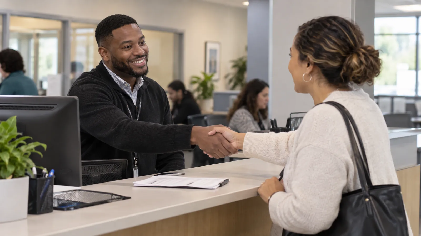 A public-service worker welcomes a visitor across a reception counter.