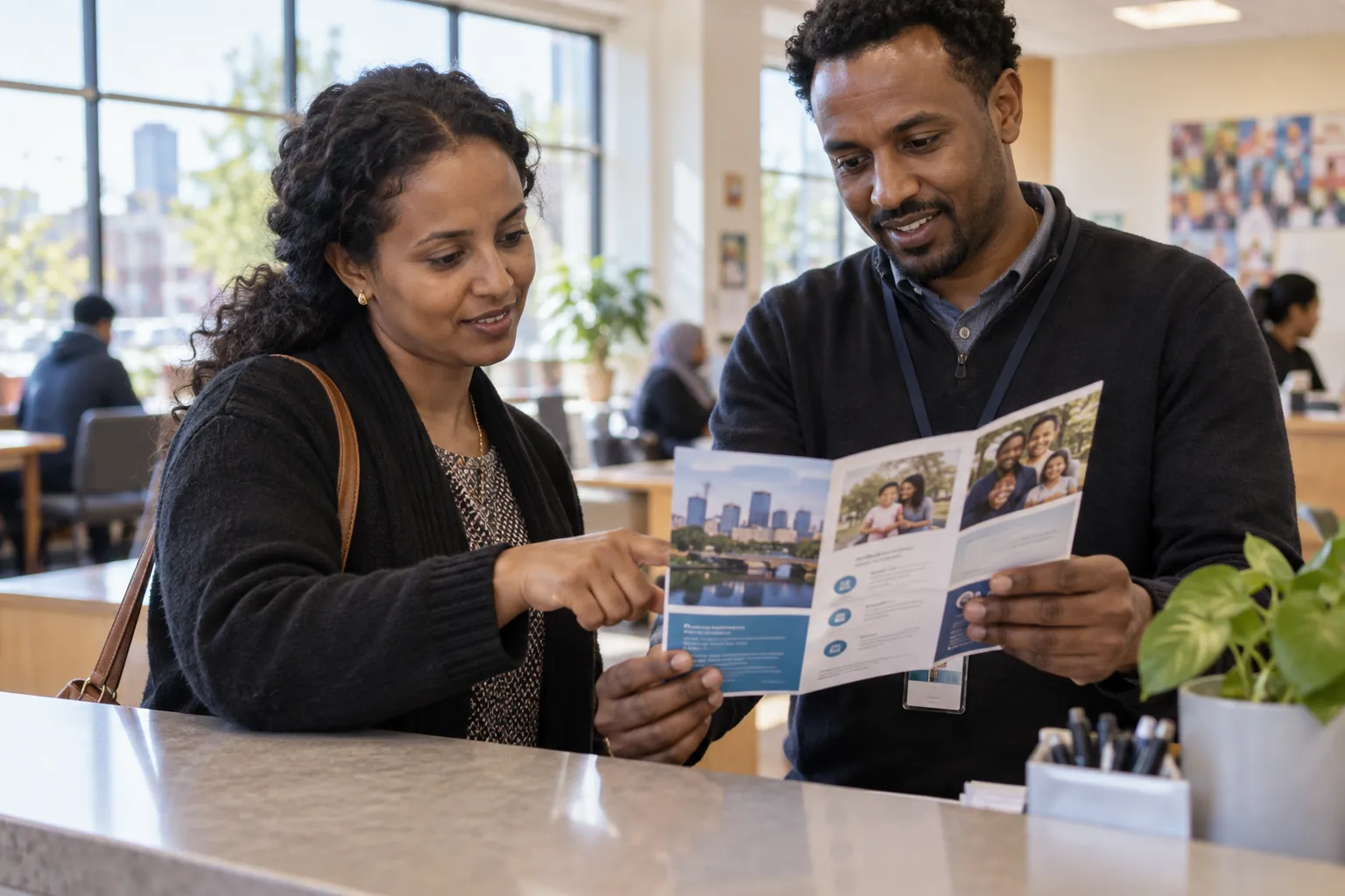 A visitor and service navigator review a community service flyer at a counter.