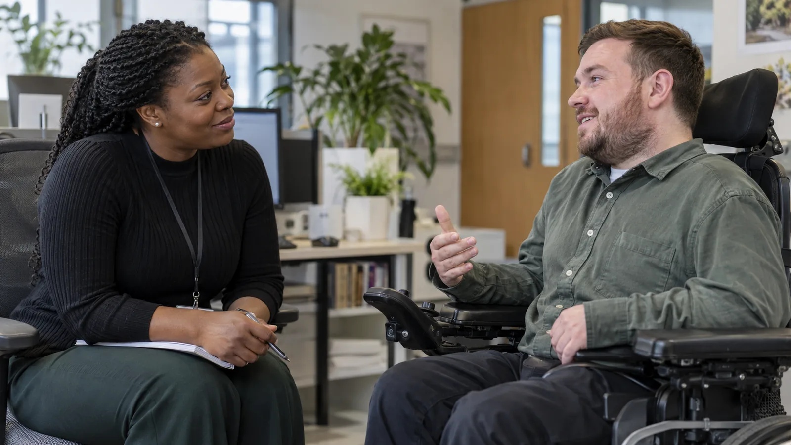 A staff member and wheelchair user speak with one another at eye level.