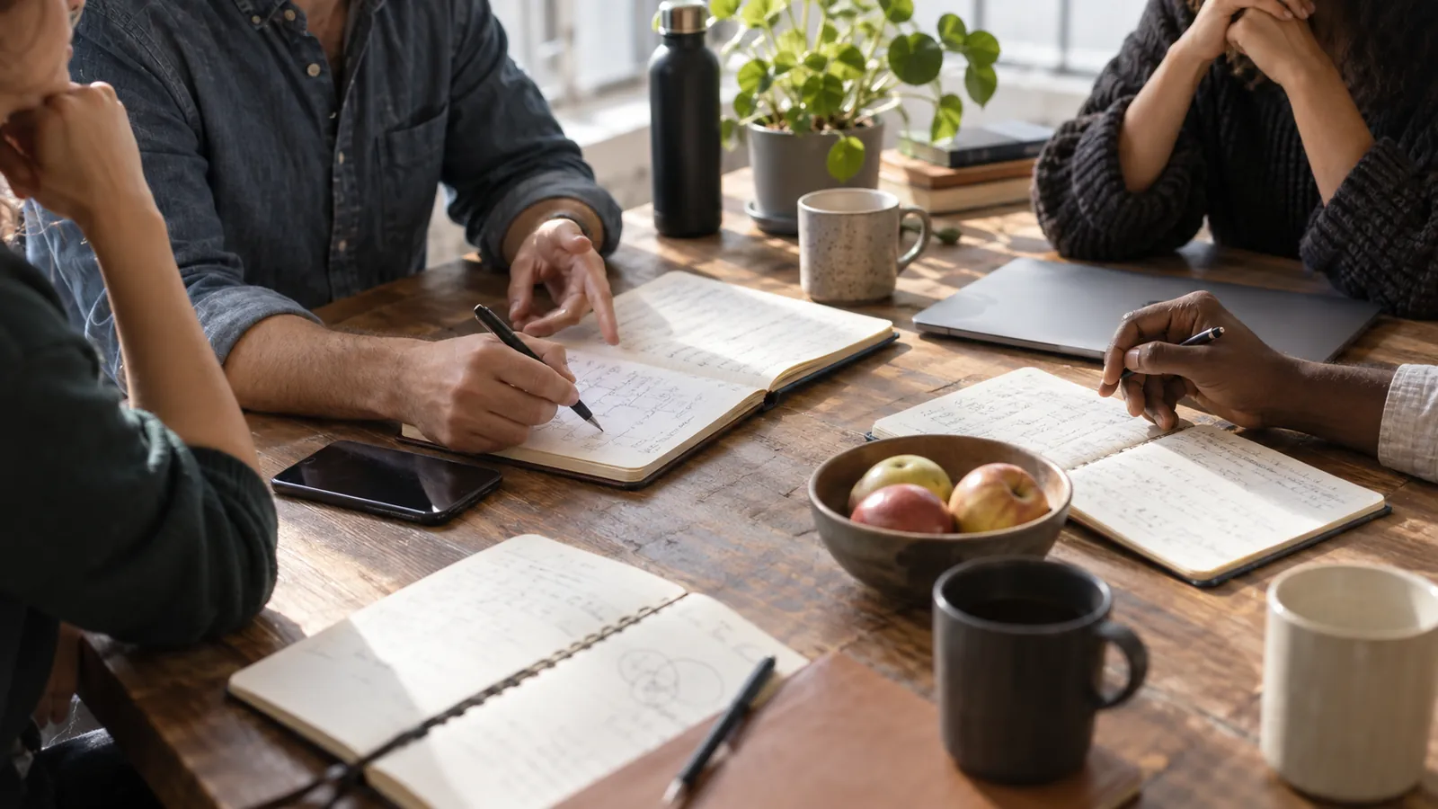 Colleagues compare notes and perspectives around a shared worktable.
