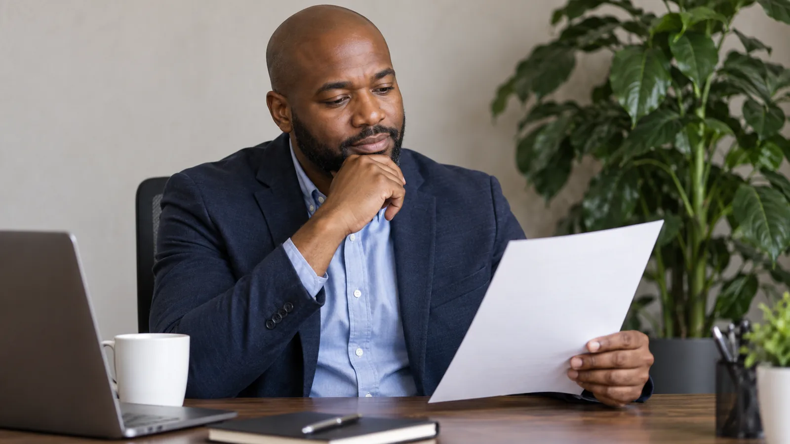A manager reflects while reviewing feedback in a private office.