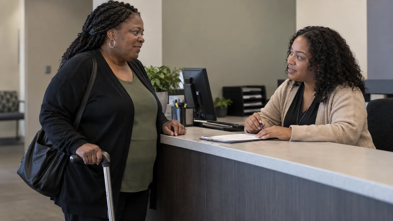 A visitor using a cane talks with a navigator at a service counter.