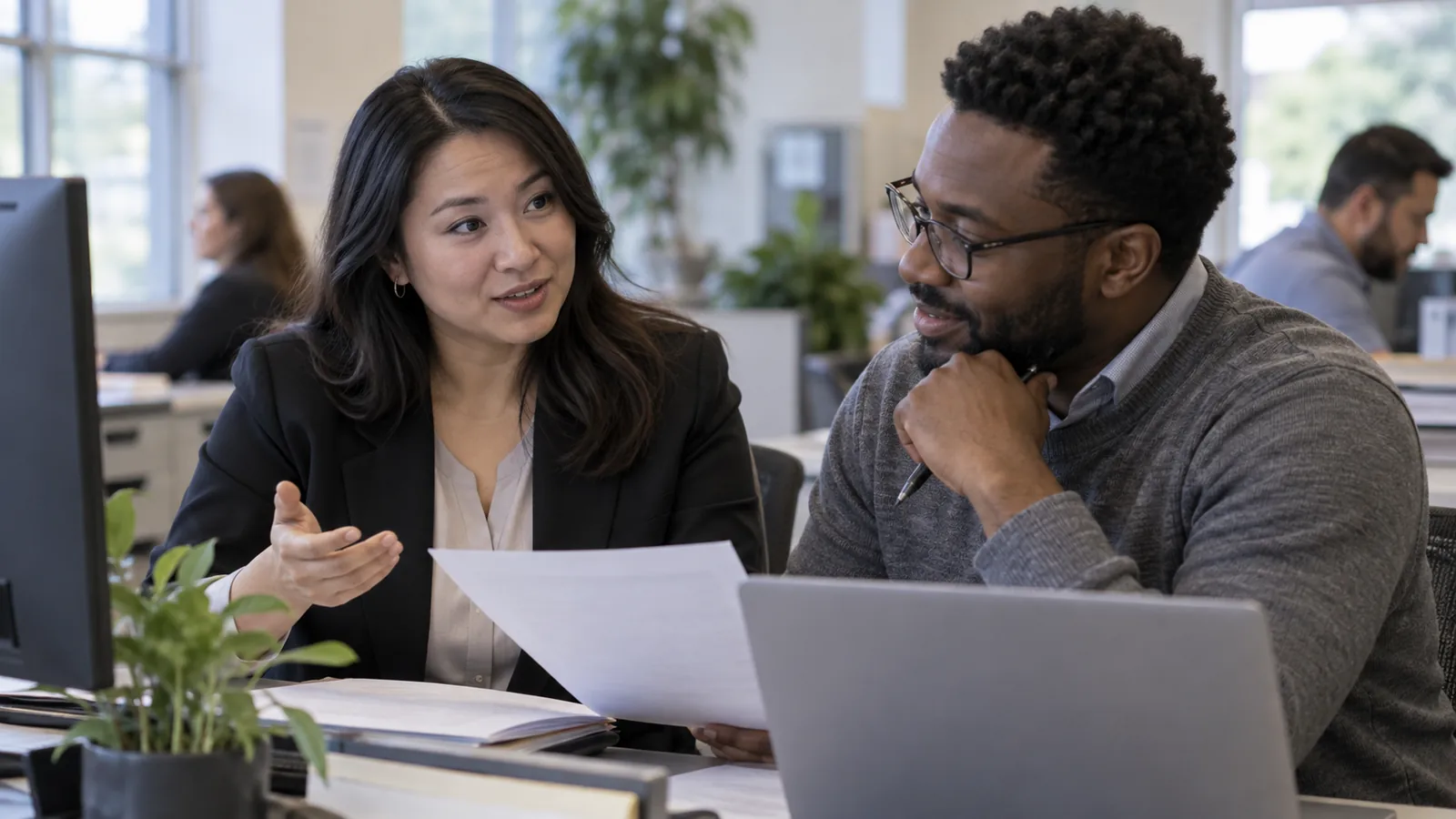 Two colleagues discuss a document in an office.