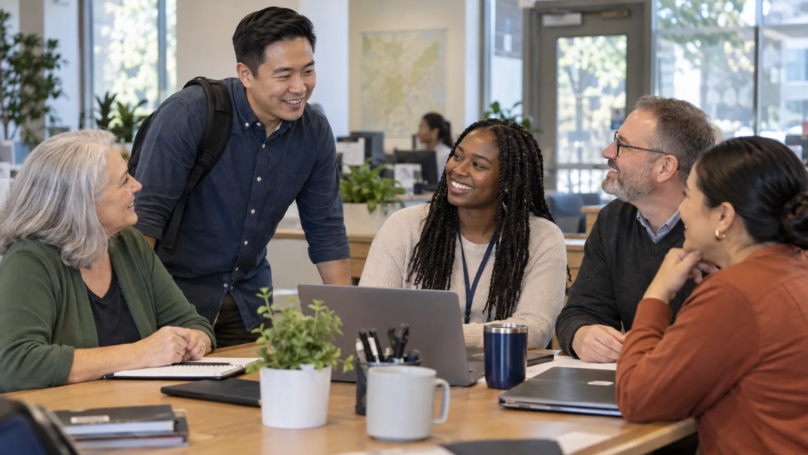 Colleagues of different ages and backgrounds share a conversation around a laptop.