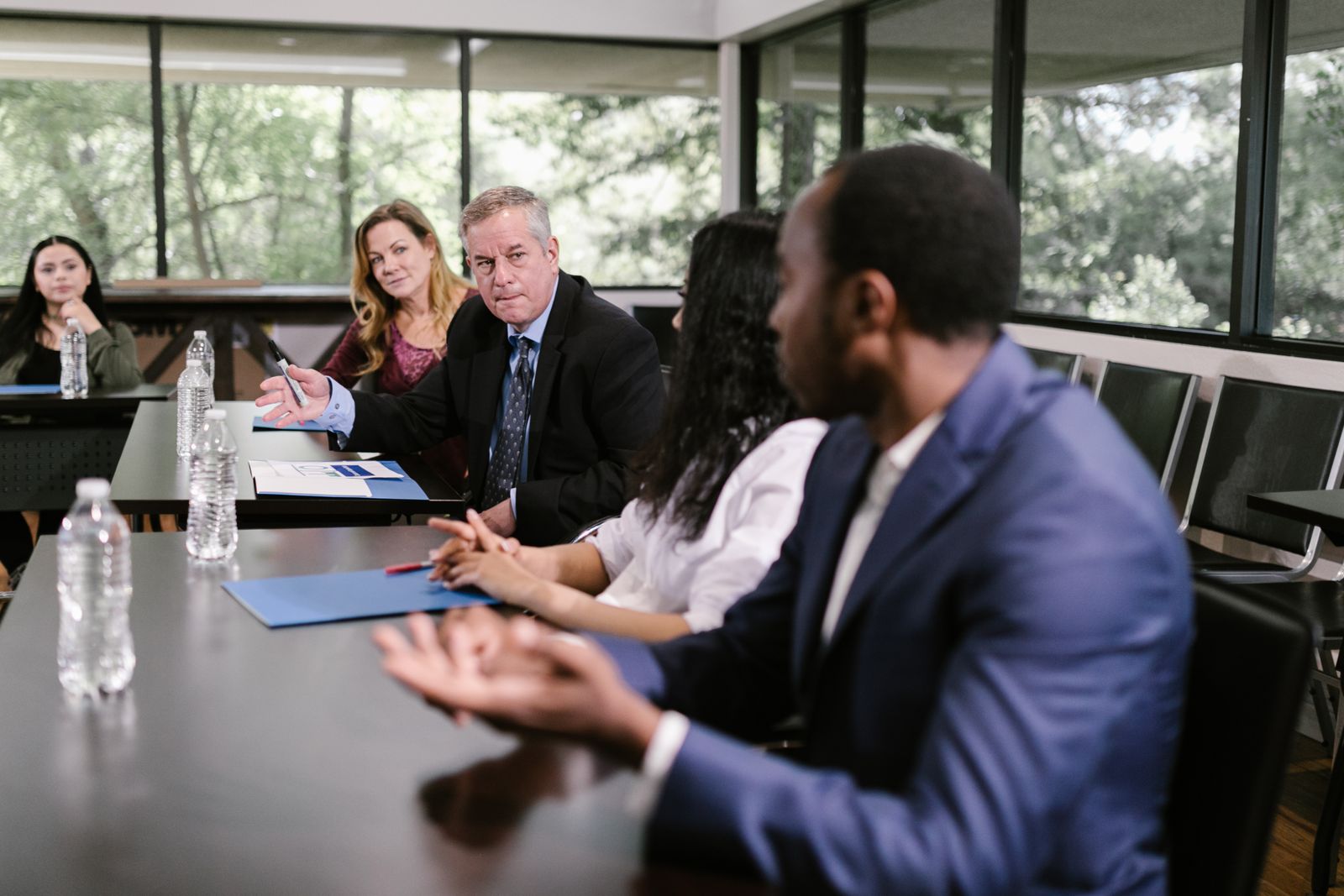 A colleague presenting to two others at a whiteboard during a meeting.